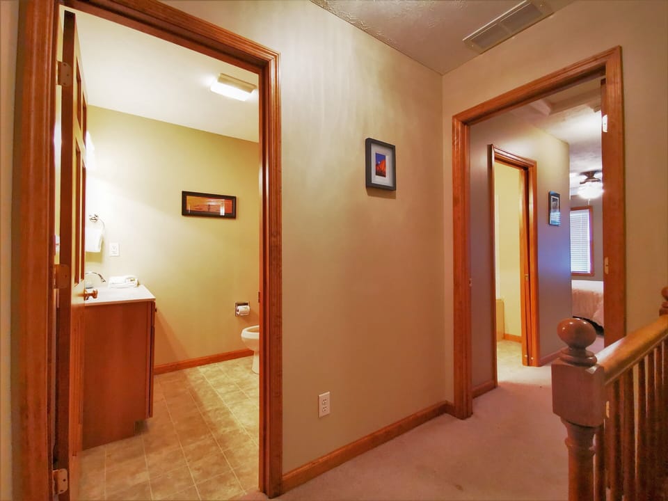 Hallway connecting bedrooms and bathroom with warm wooden accents