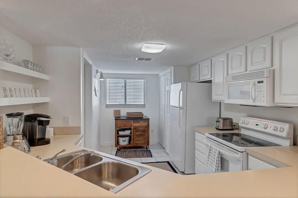 - Enjoy a fully stocked kitchen with white cabinetry, open shelves, and all essentials
- Coffee maker, blender, toaster, and microwave ready for easy mornings
- Welcoming and functional space that opens right into the heart of the condo