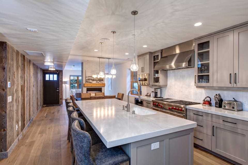 Prepare meals in our fully equipped kitchen, featuring a large island with bar seating, modern stainless steel appliances, and stylish two-tone design. All the essentials for a great stay.