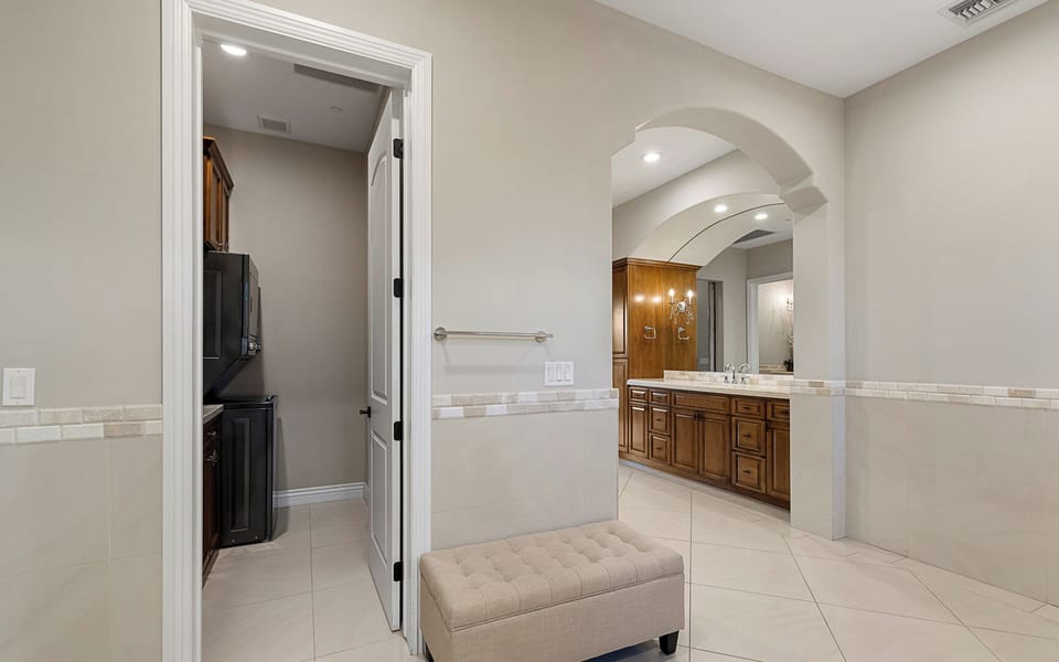Primary en-suite with washer/dryer, bench, and tiled floors to luxurious bath