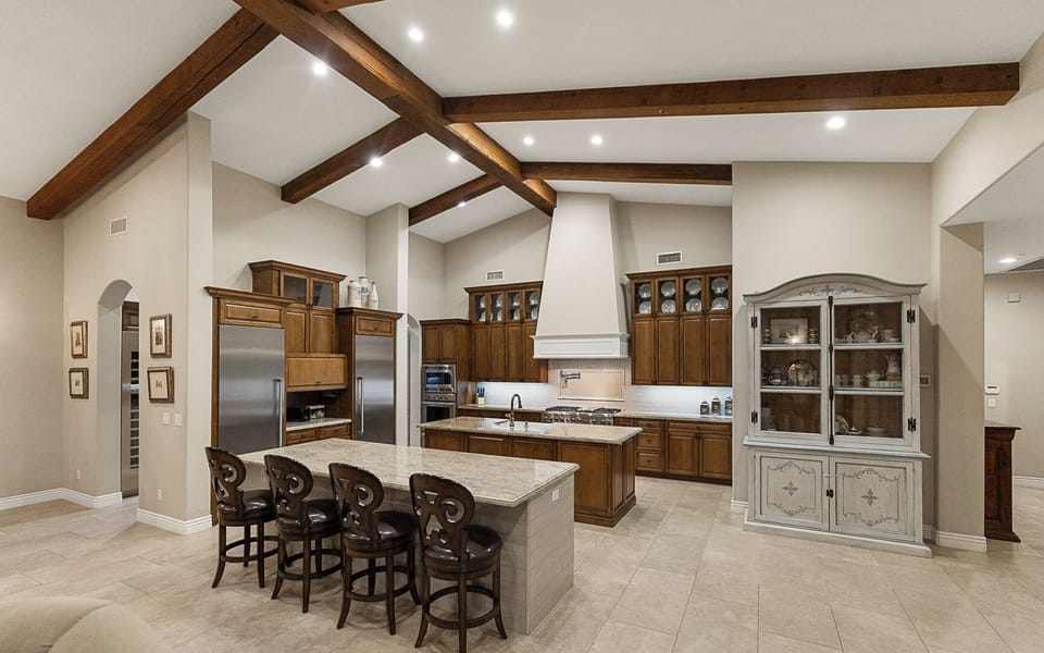 Open kitchen with double islands, granite counters, appliances, and dining area
