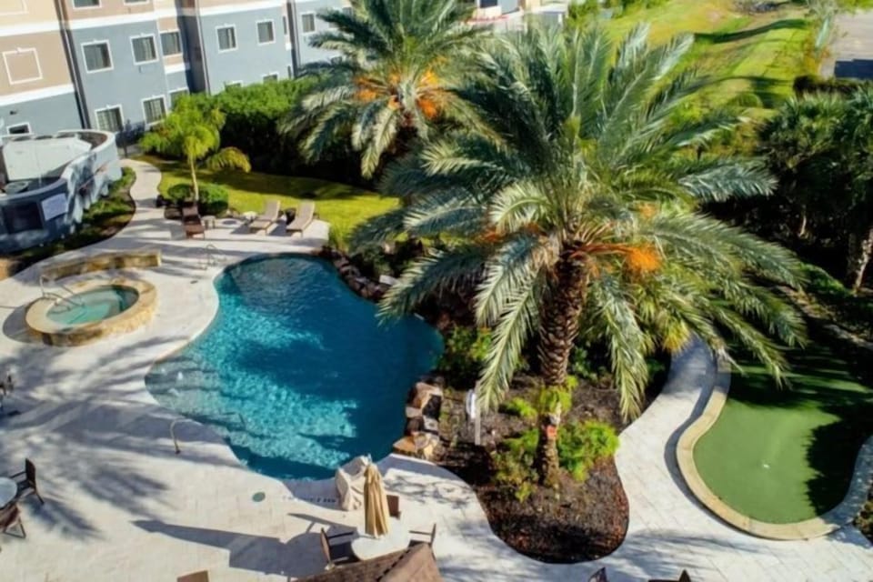 Aerial view of outdoor pool, hot tub, and lounge area with umbrellas