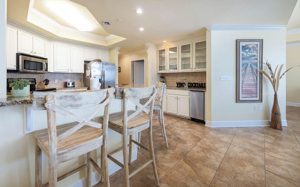 Spacious kitchen with stainless appliances, granite countertops, and rustic bar stools for casual dining