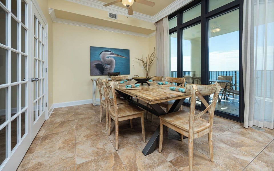 Stylish dining area featuring a rustic wooden table, coastal decor, and expansive windows showcasing impressive views