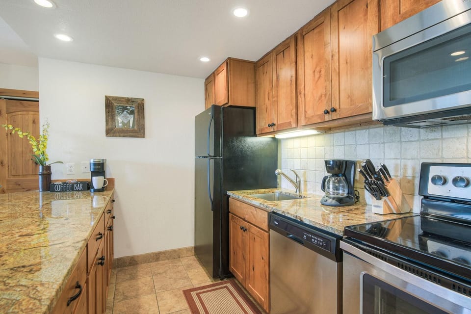 Granite countertops and wood cabinetry frame the kitchen, featuring a stainless steel oven and dishwasher.