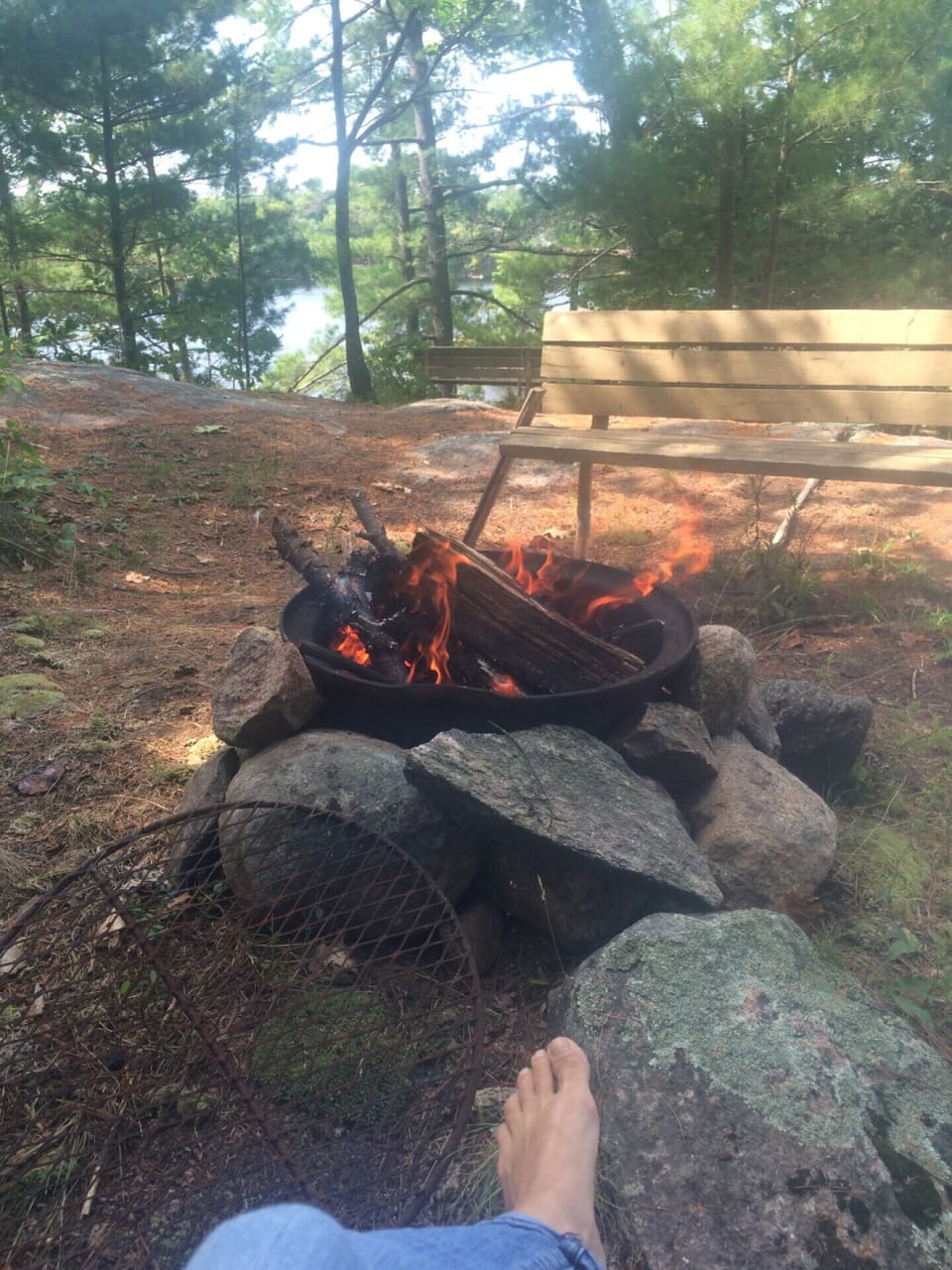 There is a fire pit with a view of the lake. There is lots of chairs for seating.