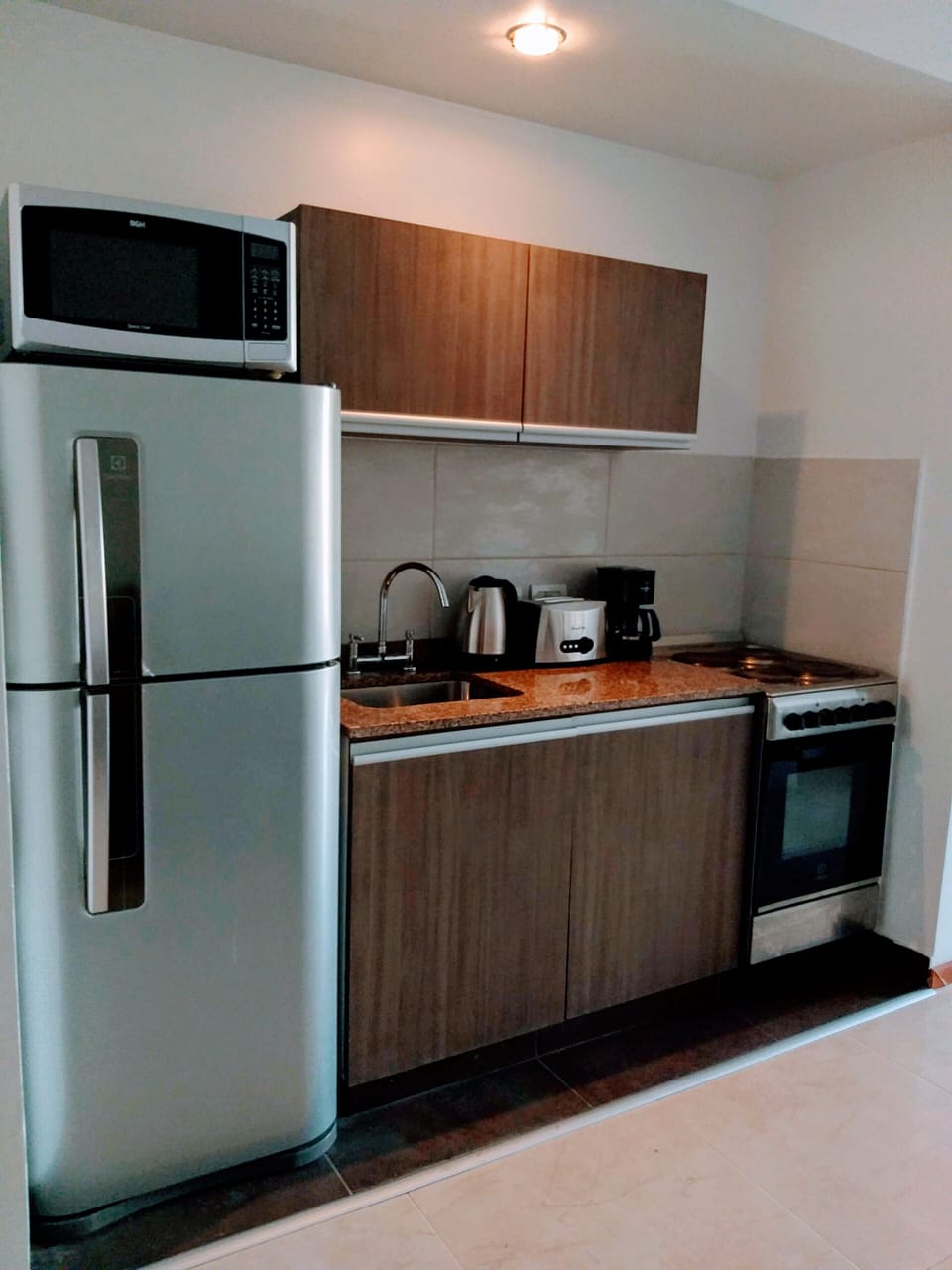 Kitchen with refrigerator, micro oven, coffee maker, electric kettle, and oven.