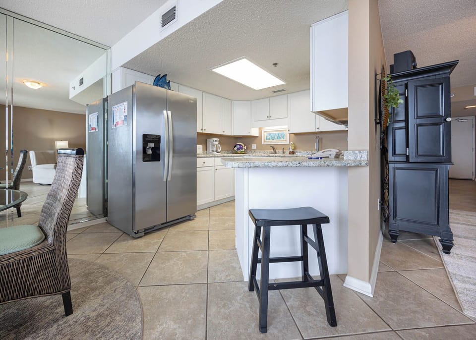 Bright kitchen area features a granite countertop, stainless appliances, and a breakfast bar with seating for casual dining