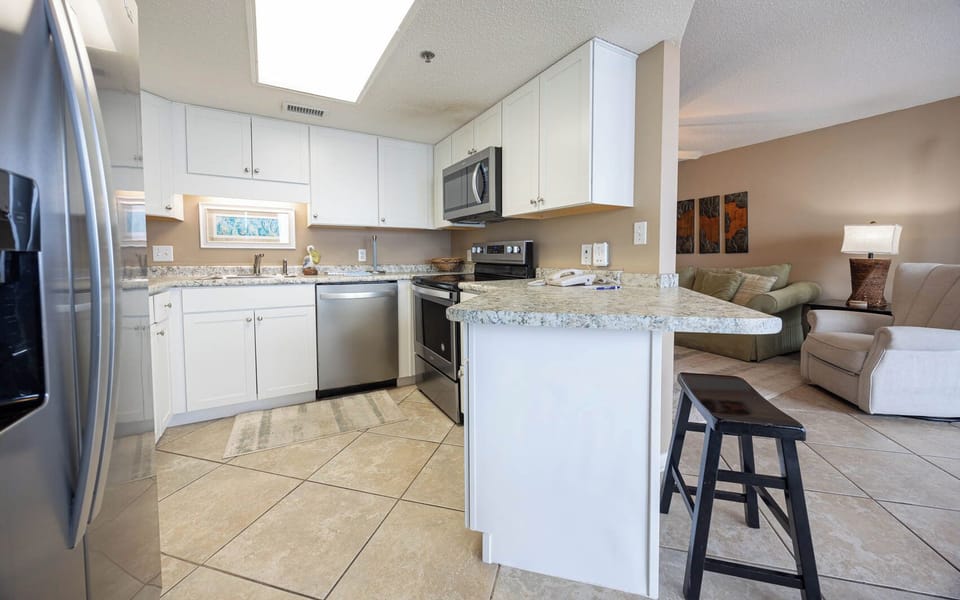 Modern kitchen features granite countertops, sleek appliances, and a breakfast bar with seating