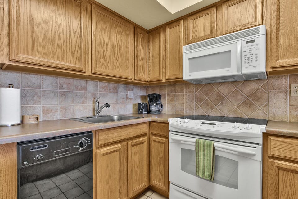 Kitchen with coffee maker, toaster, dishes, cups, glasses, cooking pots & pans.