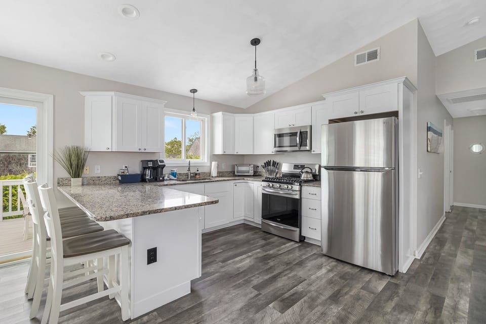 Stainless steel appliances throughout open kitchen opening to elevated deck.
