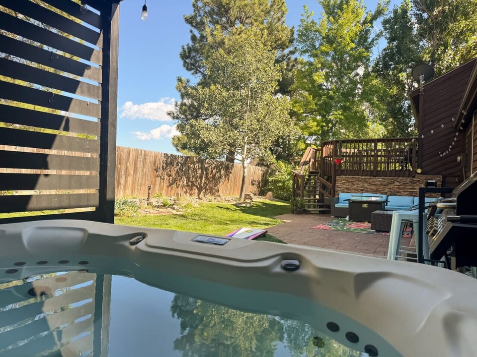 Peaceful hot tub in fully fenced backyard, with plenty of seating, grill, and beautiful trees.