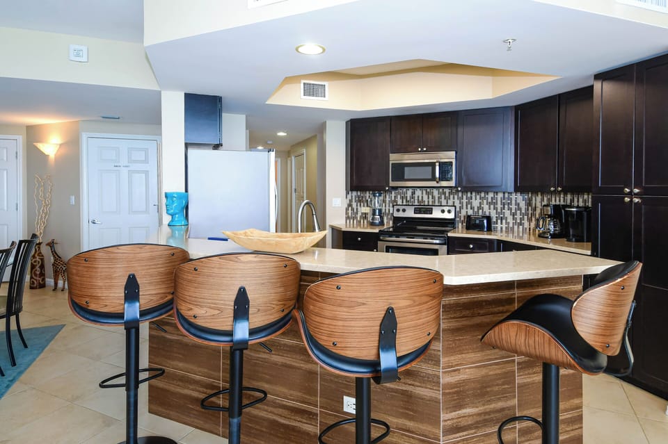 Gather at your sleek kitchen island, fully equipped with modern appliances and a chic backsplash. Curved bar seating invites easy mornings and relaxed evenings.