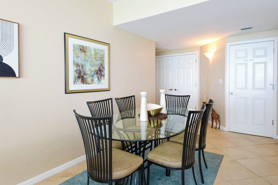 Your dining area features a stylish glass-top table with seating for six, perfectly positioned near the entrance for easy entertaining and memorable meals together.