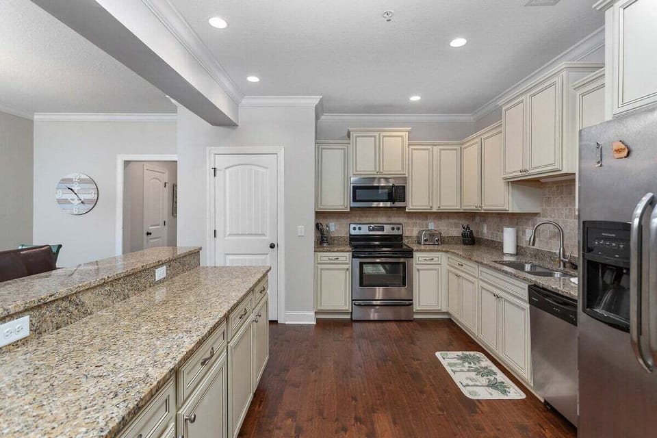 Kitchen with cream cabinets, granite island, and stainless appliances
