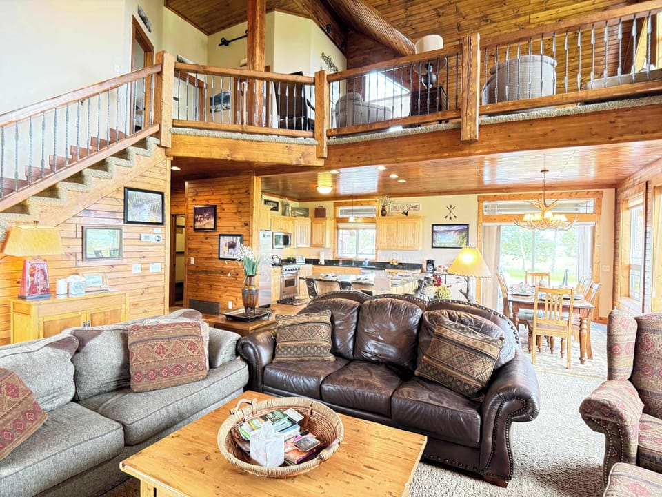 The living room offers a welcome environment to relax after a long day and connect with others. An open and inviting great room with comfortable leather seating, connecting the kitchen, dining area, and upper loft seamlessy.