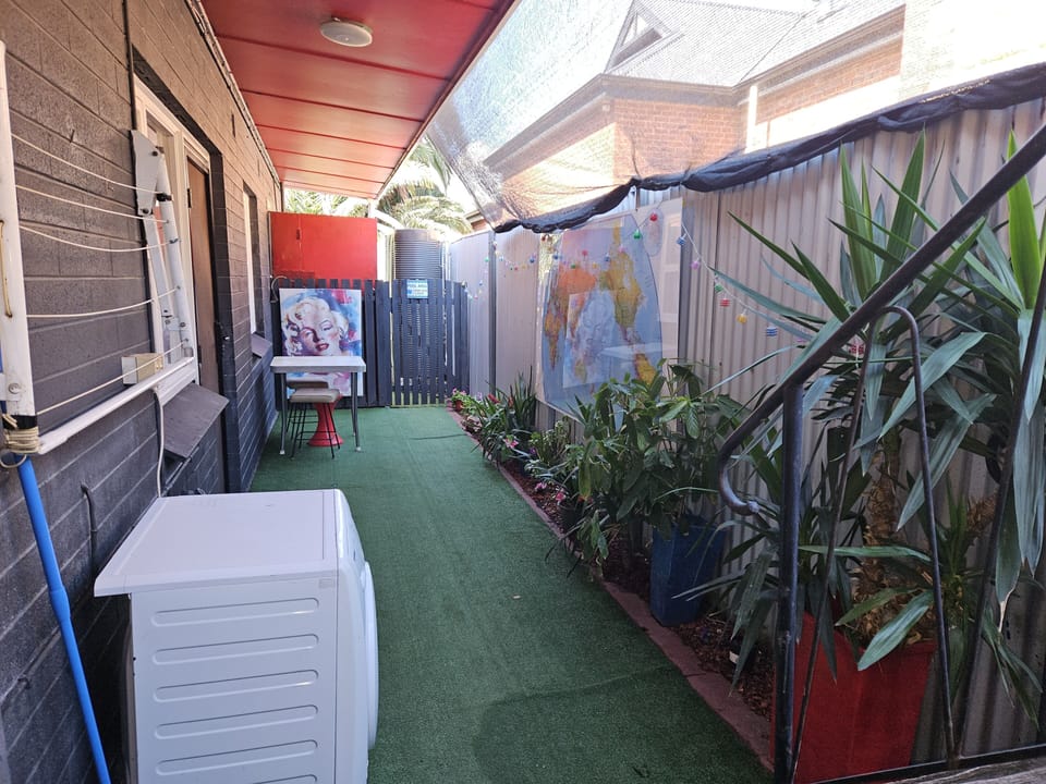 Small enclosed yard leading to larger backyard (equipped with washmachine).
