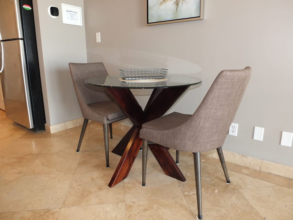 Dining table with seating for two, plus a spare chair at the bar area.