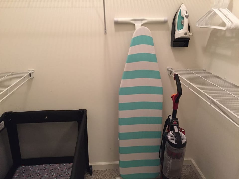 3rd floor primary closet with iron board, vacuum, and pack & play