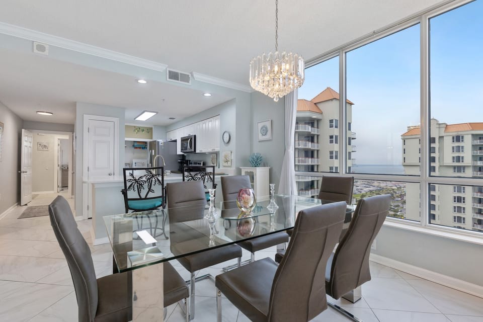 Glass-top dining room table with 6 chairs. Four extra chairs are in kitchen.