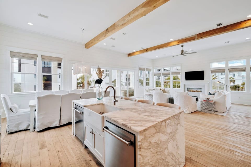 Your stunning open-concept kitchen flows seamlessly into the living area, featuring gleaming marble countertops and rustic wood beams overhead.