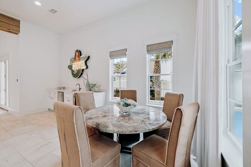 Gather around the elegant marble dining table where every meal becomes special. Natural light flows through windows offering glimpses of swaying palms.