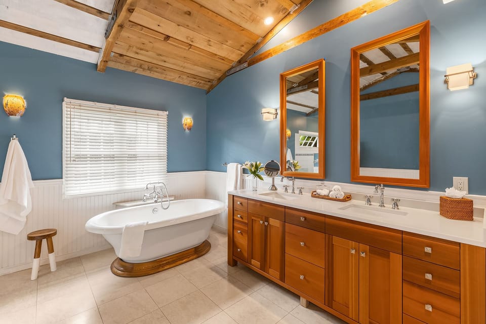 Spa-like primary bathroom with a freestanding tub, wood accents, and bold blue walls.