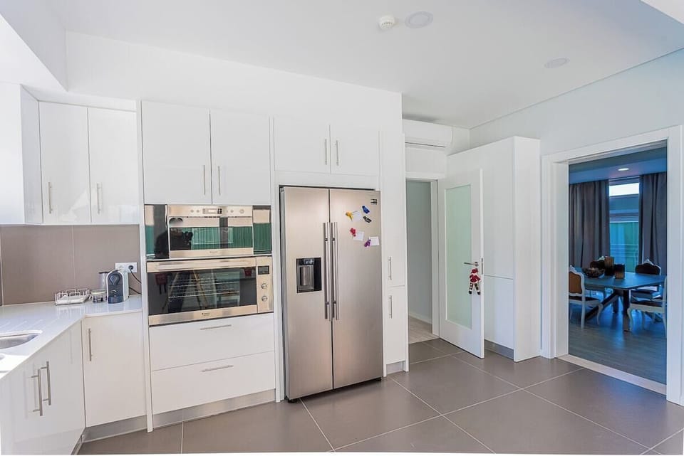 Modern kitchen with white cabinetry and stainless steel appliances — Villa Mena, luxury holiday villa in Charneca da Caparica