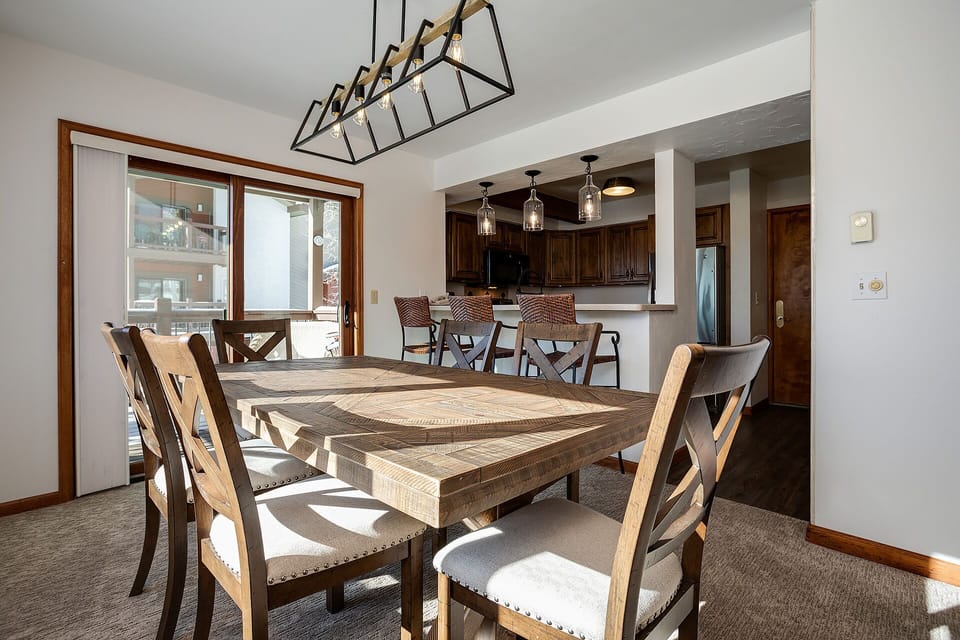 Gather around this stunning reclaimed wood dining table where your group can share memorable meals beneath the warm glow of rustic chandeliers.