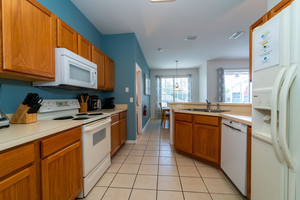 Full kitchen with white appliances and breakfast bar.