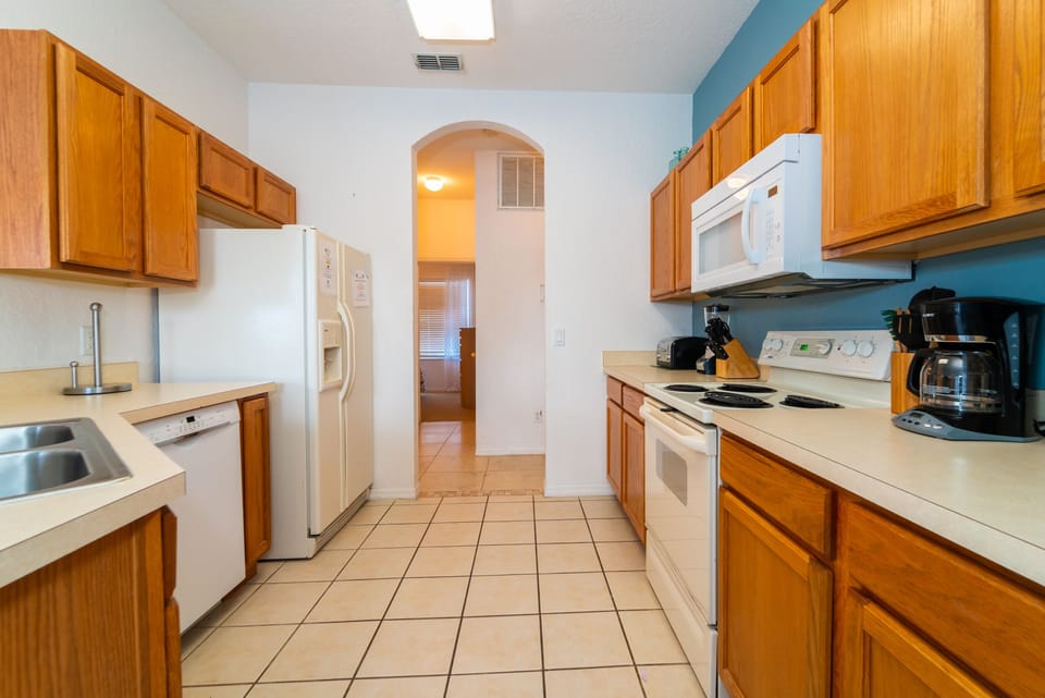 Fully equipped kitchen with white appliances with ample cabinet space.