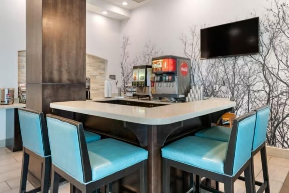 Breakfast area with turquoise bar stools, tree-branch wall mural, and mounted TV