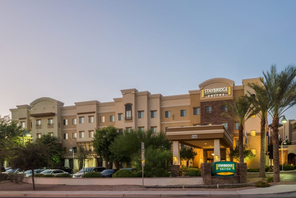 Exterior view of the three-story building amid palm trees.