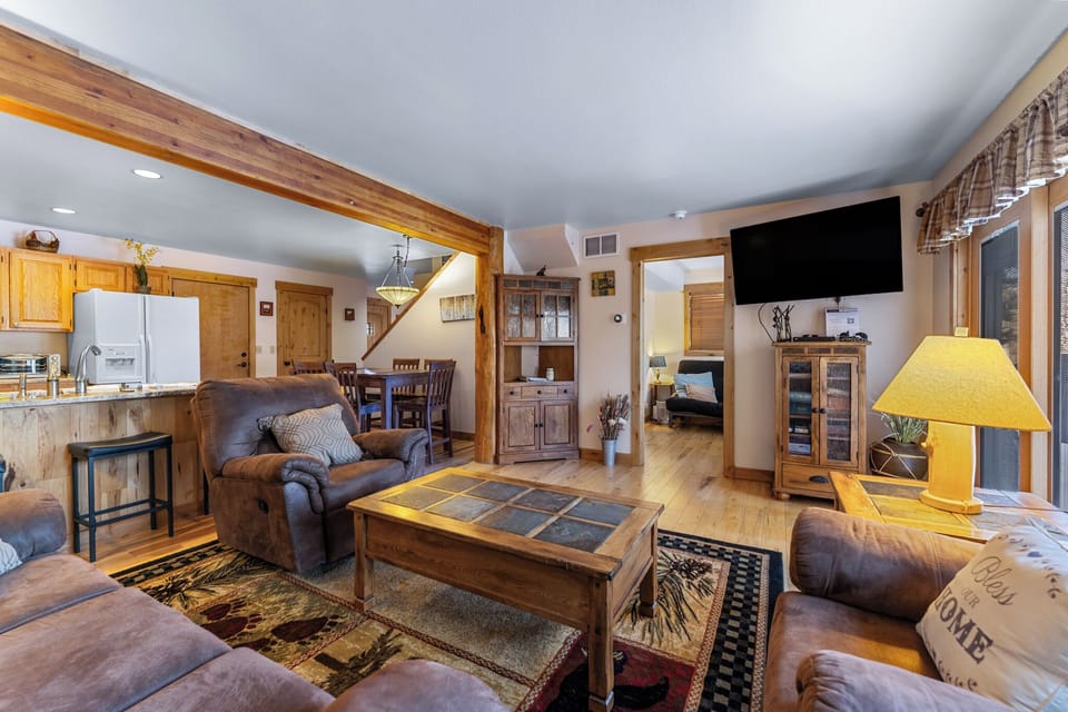 Sink into rustic comfort where warm wood beams frame your open-concept retreat, complete with cozy leather seating and mountain charm.