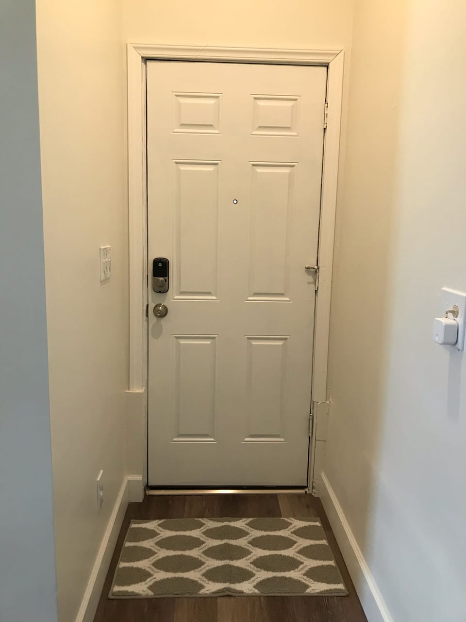 Front door featuring smart lock and peephole.