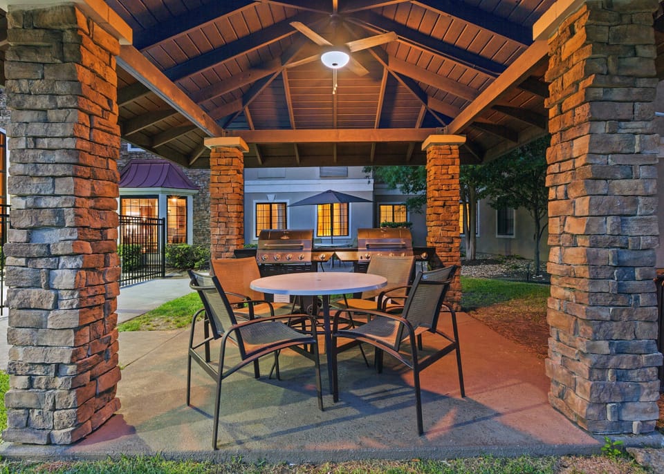 The BBQ patio is equipped with a grill, a table, and chairs, providing a great outdoor space for family cookouts.