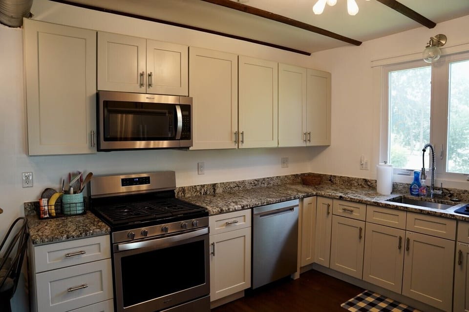 Fully equipped kitchen with a gas range, stainless dishwasher, and generous granite counters for prepping meals with ease. Bright windows and exposed beams add charm, while everything you need for cooking is stocked and ready for your stay.