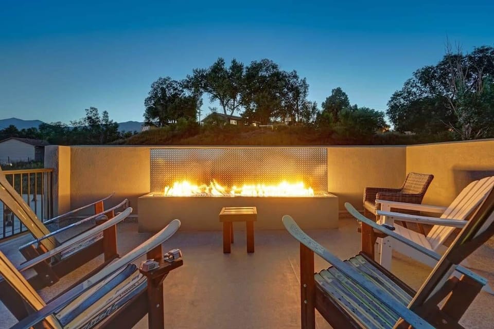 Rooftop fire feature anchors this gathering space, surrounded by comfortable chairs where evenings naturally stretch longer with warm light, quiet conversation, and the glow of the flames.