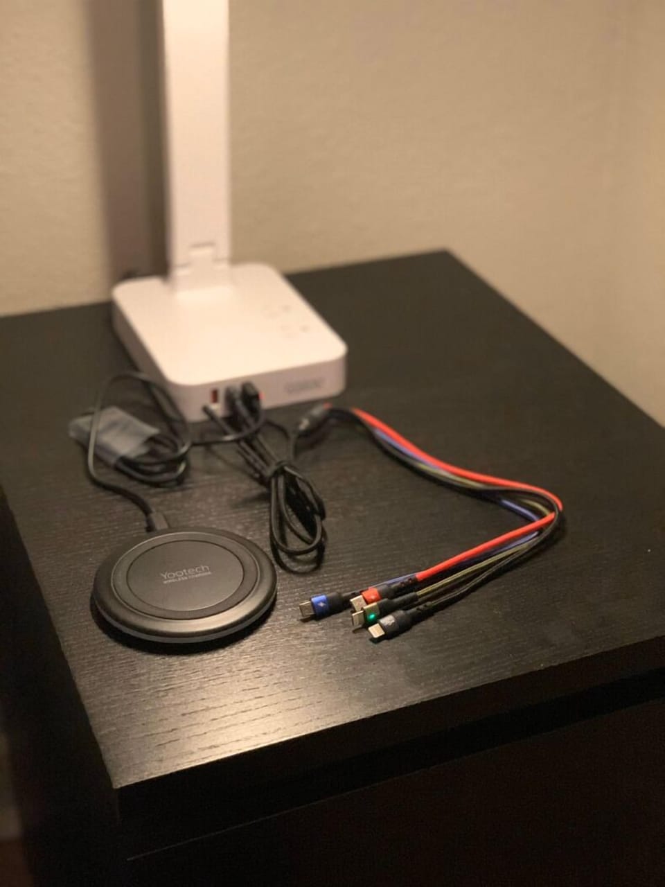 Nightstand with two power outlets, a wireless charging pad, and charging cables.