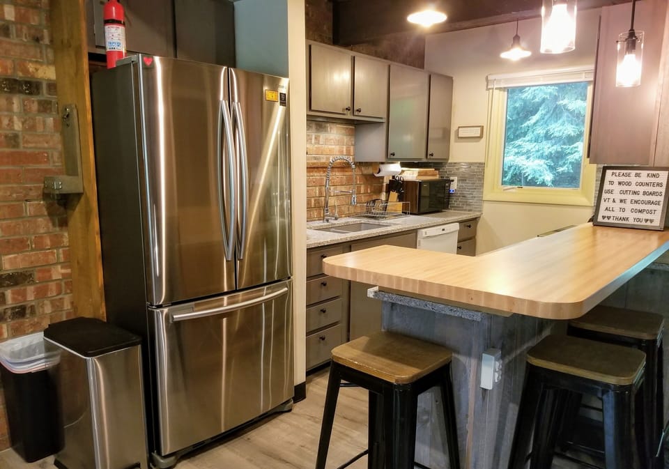 Quartz counters, double sink, stainless steel fridge, butcherblock breakfast bar
