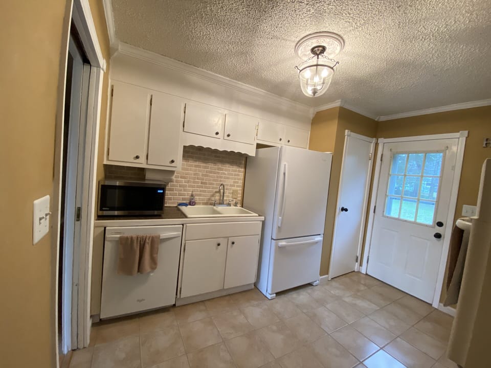 Another view of the kitchen with door leading to a large fenced in backyard