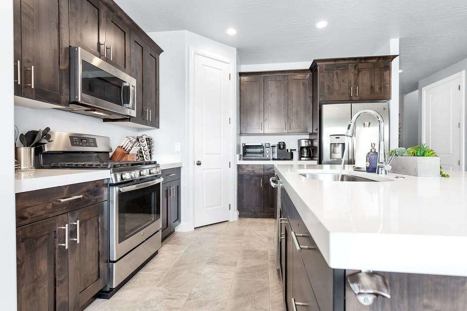 Fully stocked kitchen with stainless steel appliances and thick solid-surface countertops opening to the great room