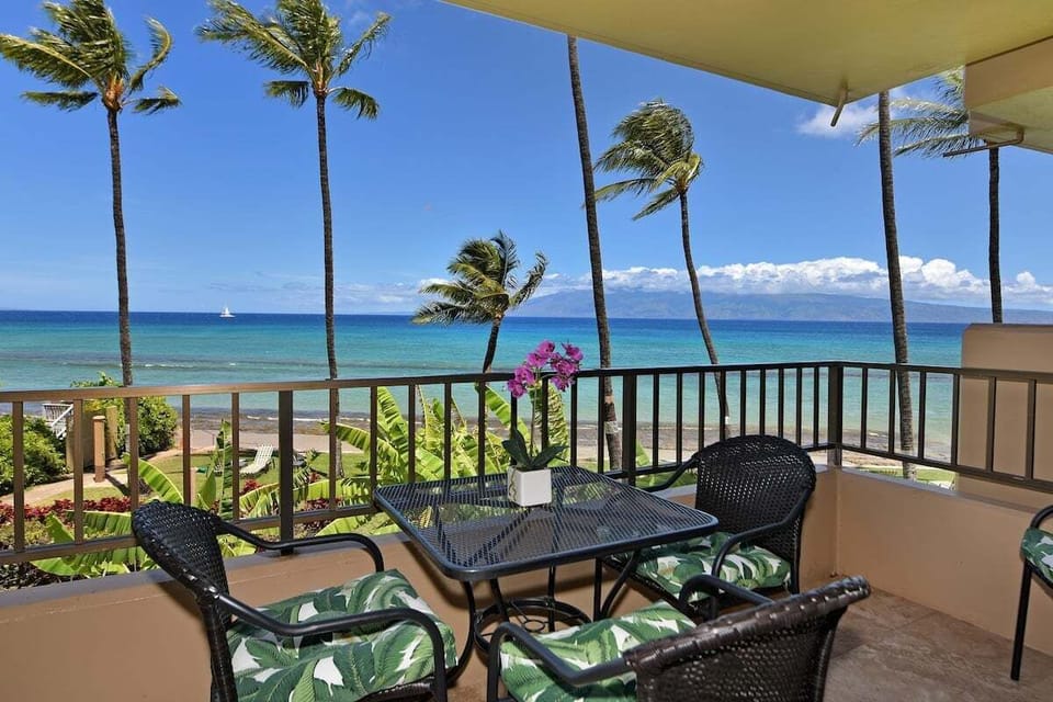 Balcony with table and orchid centerpiece overlooking ocean and palms.