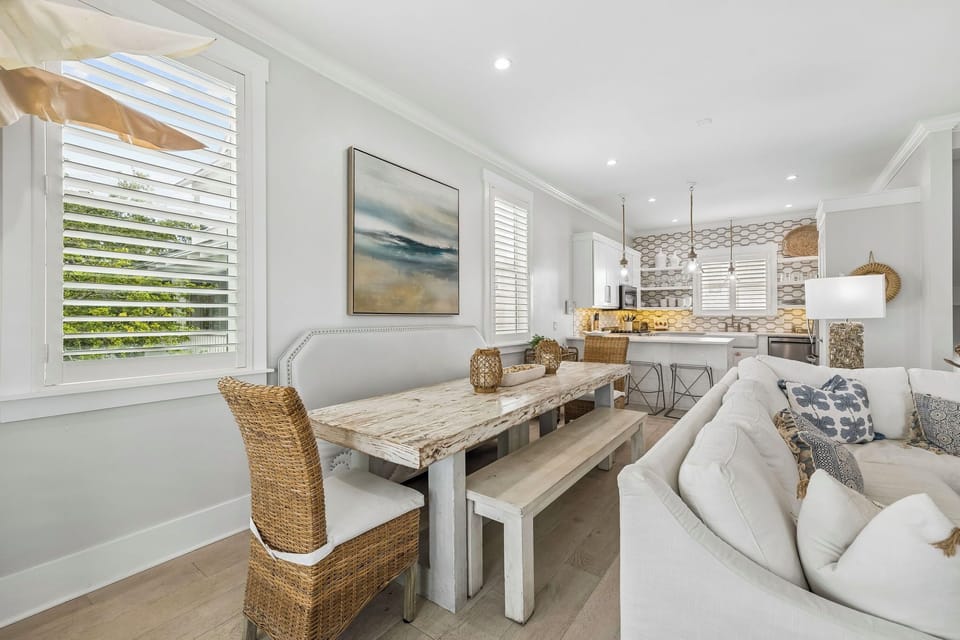 Settle into your bright, coastal-chic living space where white shiplap meets soft neutrals. Gather around the rustic dining table or sink into the plush sofa—your breezy retreat awaits.