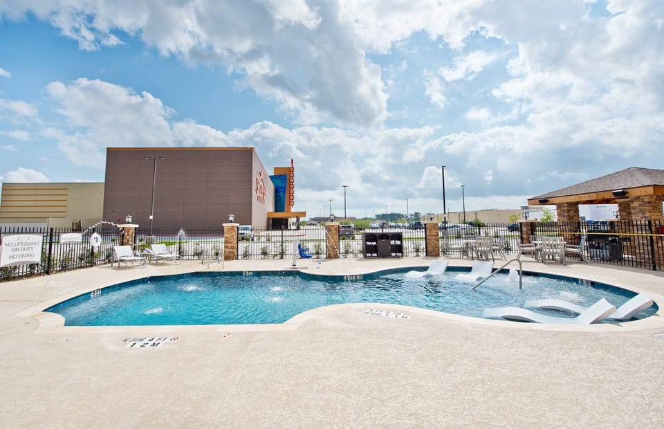 Heated outdoor pool with lounge chairs and patio seating — a cool escape after exploring Humble