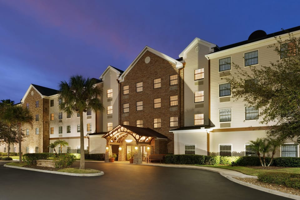 Embrace comfort with welcoming outdoor lighting, nestled palm trees, and easy access to your home away from home