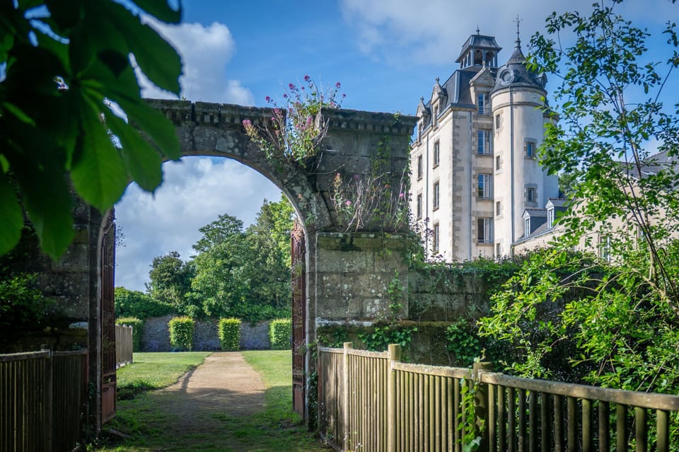 A vine-covered archway opens onto a path leading toward the tower.