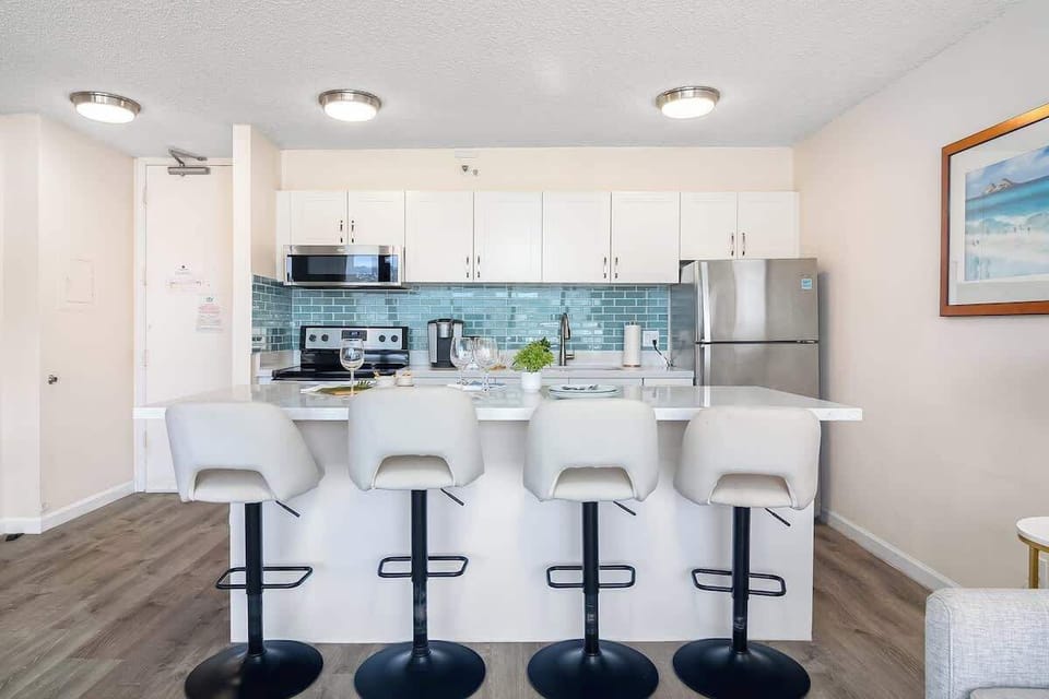 Modern kitchen with a blue tile backsplash and seating for four at the island