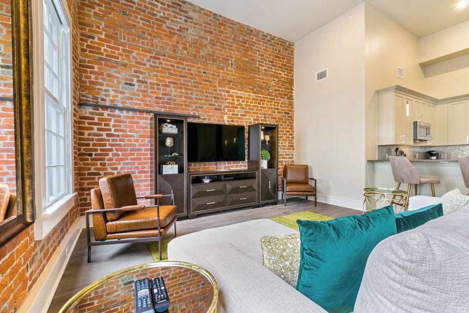 Open-concept living, kitchen, and dining area with ample seating. Relax on a large sectional and enjoy a 65” Samsung Smart 4K TV with streaming and DIRECTV Entertainment. Dining table seats six, plus bar seating for four. Plenty of natural light!