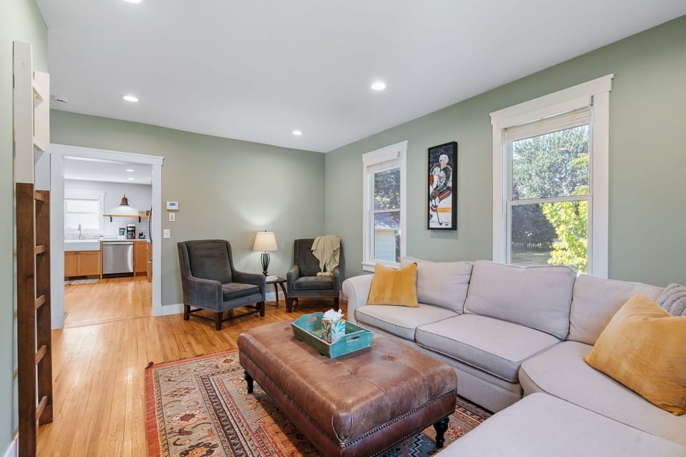 Sink into the plush sectional sofa with golden pillows and enjoy natural light streaming through large windows in your peaceful living space.